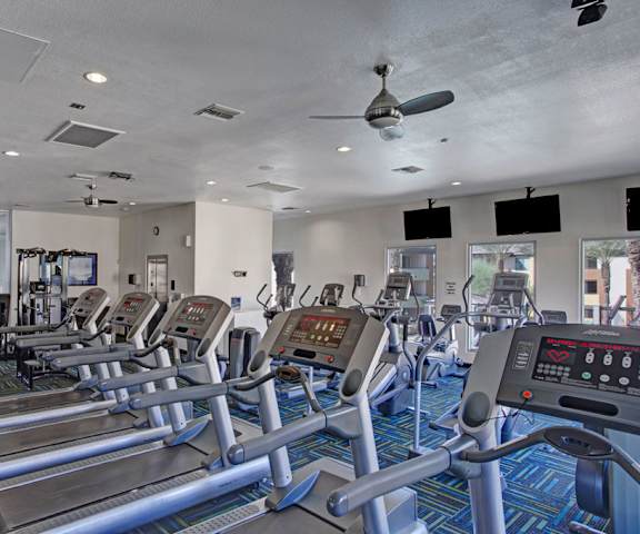 A gym with cardio equipment and flat screen televisions at Aspire Pinnacle Peak. 