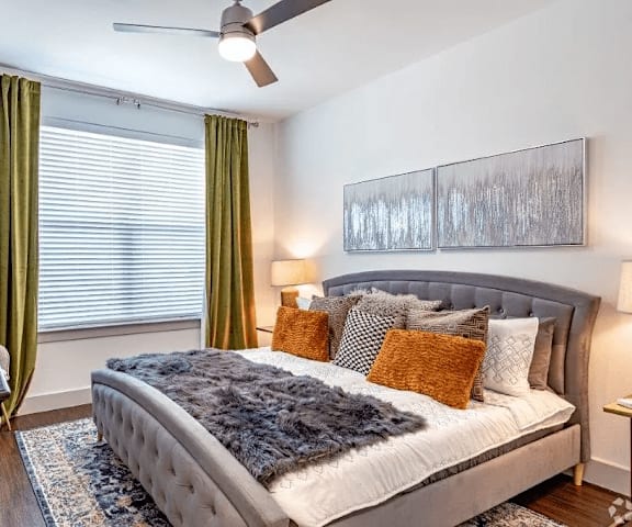 a bedroom with a bed and a window with green curtains