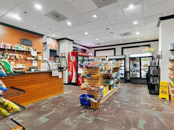 A supermarket with a variety of products on the shelves and a refrigerator in the background.