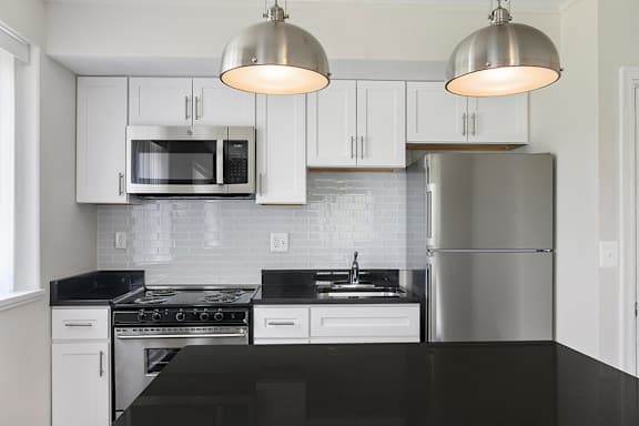 A kitchen with a black countertop and white cabinets.