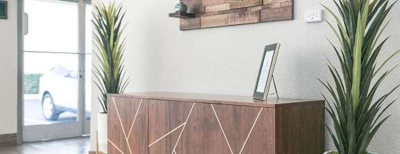 A wooden reception desk with a picture frame on top and two potted plants on either side.