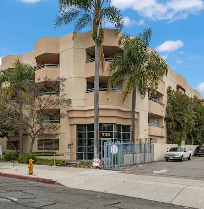an apartment building with palm trees and a yellow fire hydrant
