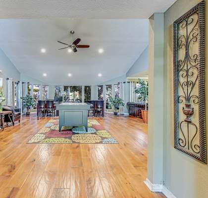 A spacious living room with a wooden floor and a ceiling fan.