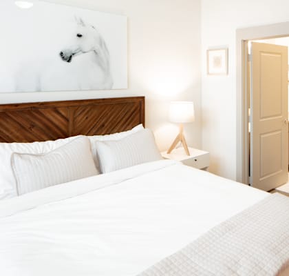 A bedroom with a large bed and a painting of a horse on the wall.