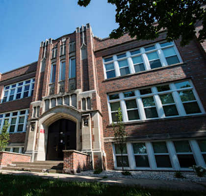 A large, old building with a tower and a set of stairs leading to a door.