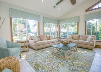 A living room with a large rug and a glass coffee table.