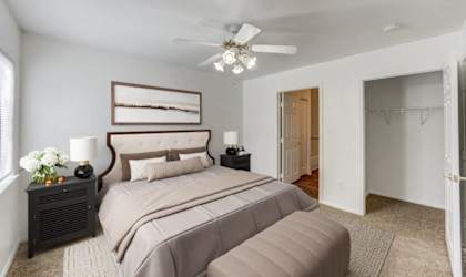 A bedroom with a large bed and a ceiling fan.