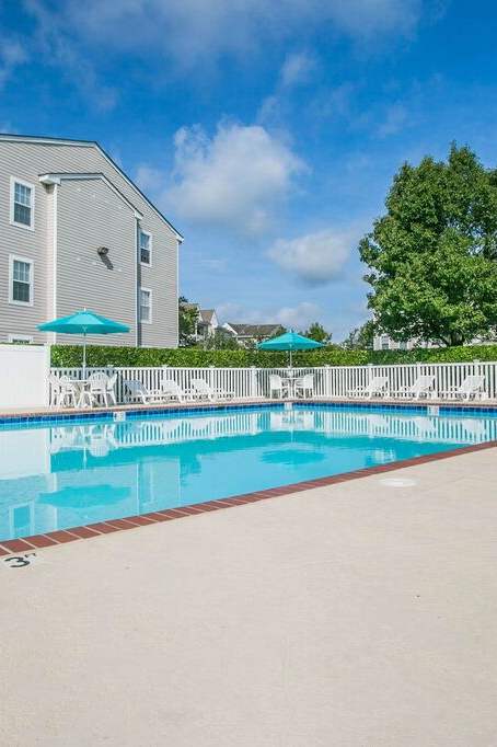 A pool with a white fence and trees in the background.