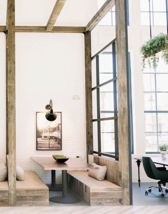 Indoor wooden pergola with wooden beams and two tables with benches on either side and oversized windows at The Merchant Apartments, Charleston, SC, 29403