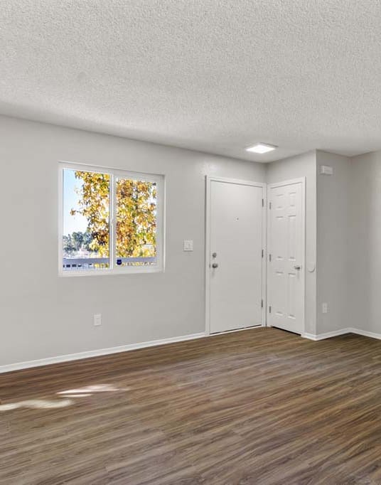 an empty bedroom with hardwood floors and a door to the bathroom at Aspire Redlands, Redlands, 92374