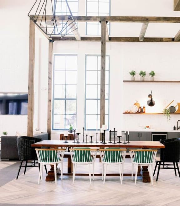 Resident lounge with high ceilings and wooden pergola with various cafe seating and farm tables at The Merchant Apartments, South Carolina
