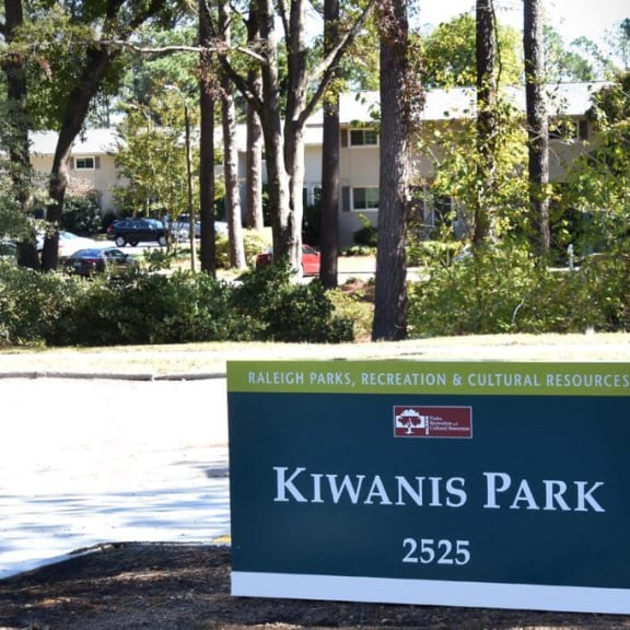 a sign for kiwis park in front of trees at Parkside at Five Points Apartments, North Carolina