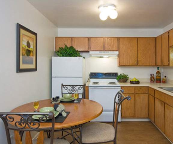 A kitchen with white appliances, light counter, and spacious wooden cabinets at Hyde Park North Apartments. 
