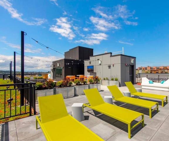 A view of the bright green sun chairs with the rest of the couches and chairs on the gorgeous rooftop balcony at Vive Apartment Homes. 