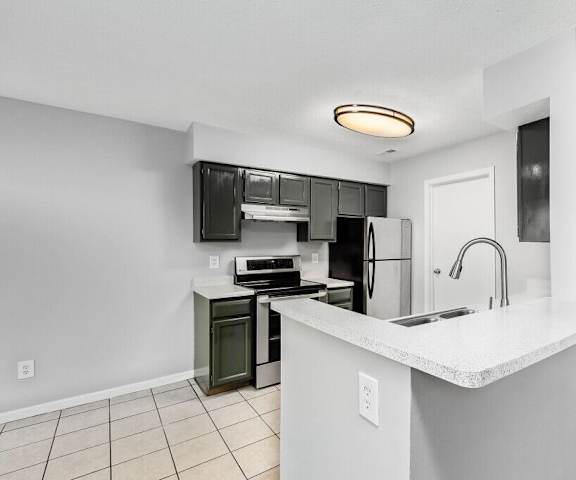 A kitchen with white countertops and black appliances.