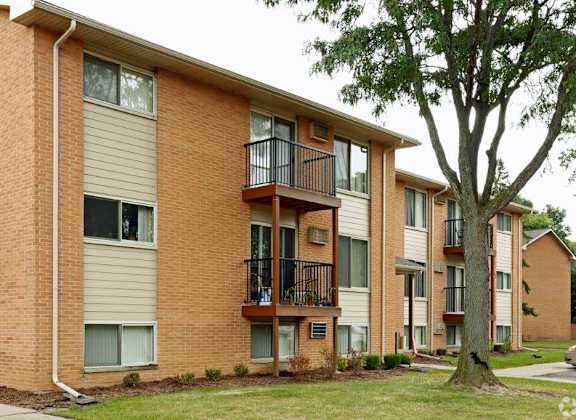 a brick apartment building with balconies and a tree