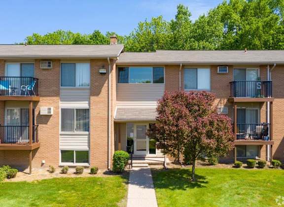 the outlook of an apartment building with green grass and trees