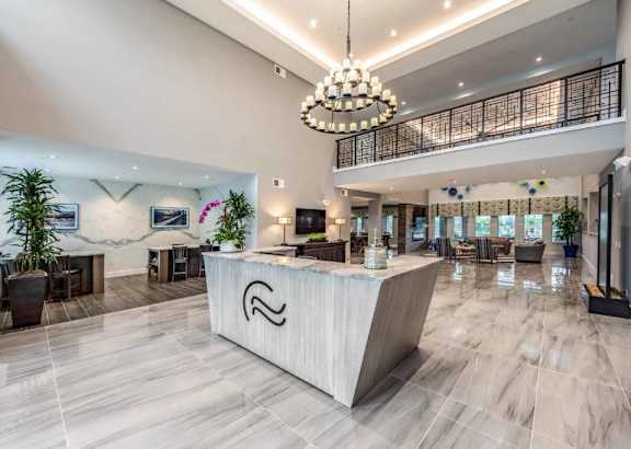 A reception area with a white reception desk and a chandelier hanging from the ceiling.