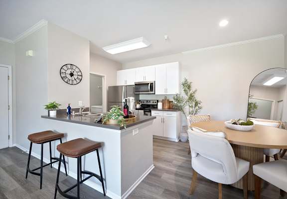 A kitchen with a bar area and a dining table with chairs.