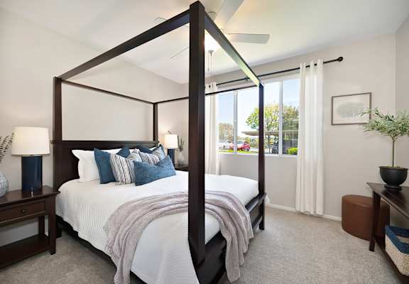 A bedroom with a four poster bed and a window with curtains.