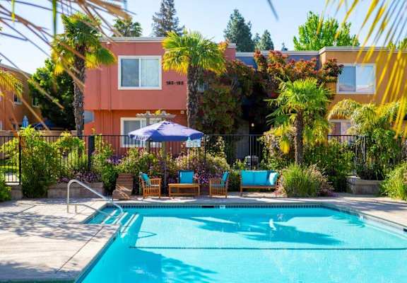 a pool with chairs and an umbrella in front of a building