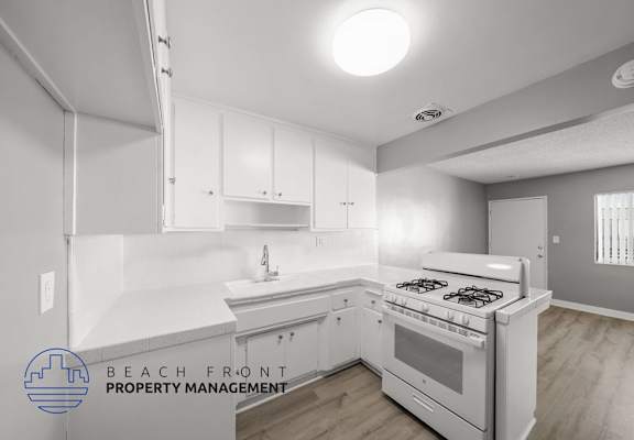 A modern kitchen with a stove top oven and white cabinets.