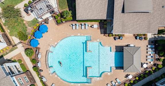 an overhead view of a swimming pool at a resort with umbrellas and chairs