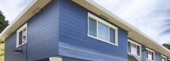 A blue house with white trim and windows.