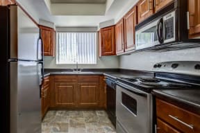 The Palms Apartments Kitchen with dark wood cabinets and stainless appliances