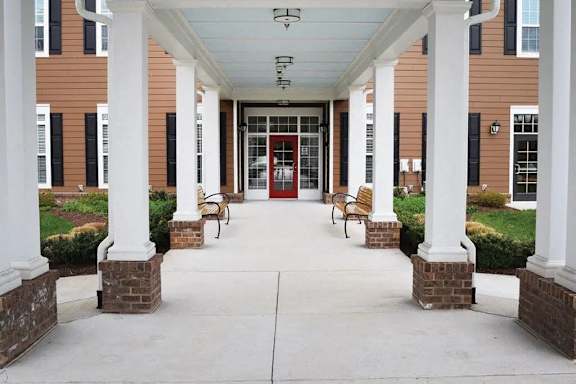 the front porch of a building with columns and a red door