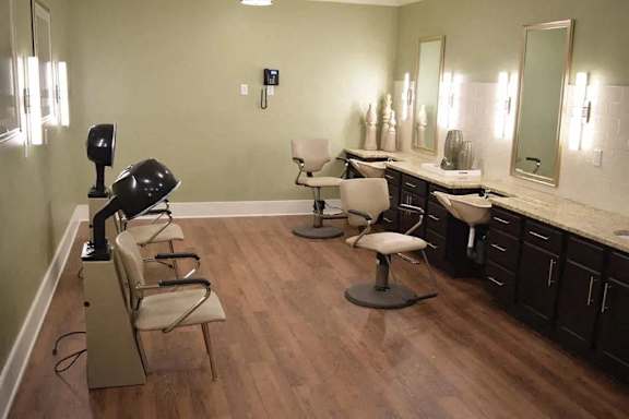 a salon room with two sinks and chairs and a mirror