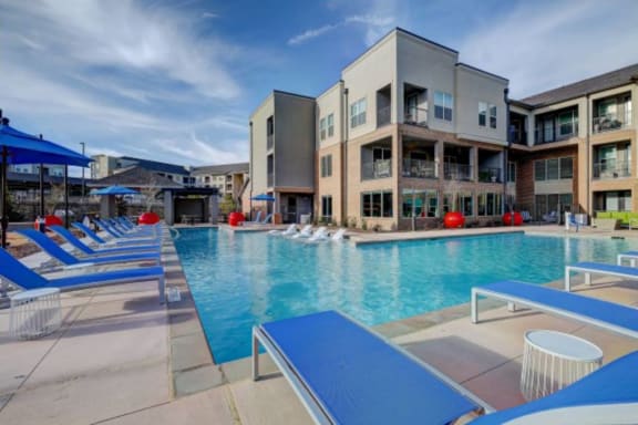 a swimming pool with blue tables and chairs at The Jane at Preston Trail, Cedar Hill, TX