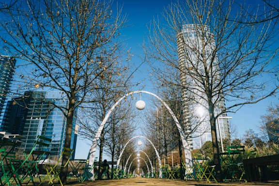 A city park with a tunnel of lights and tall buildings in the background. at Uptown by Onni Apartments, Apartments, Dallas, TX