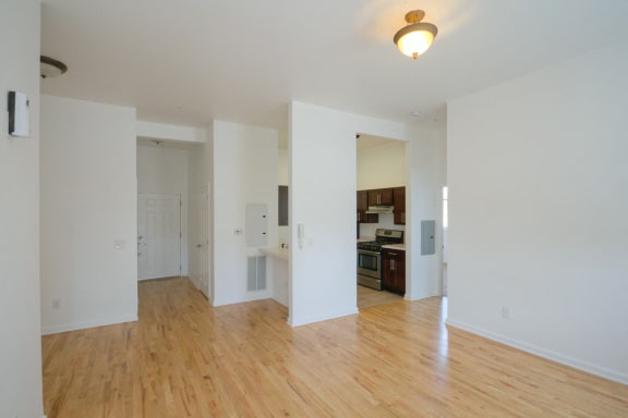 Living room with hardwood floors, white walls and view of kitchen
