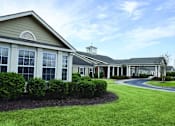 Thumbnail 5 of 5 - the front of a building with grass and bushes