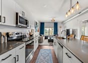 Thumbnail 4 of 26 - A modern kitchen with white cabinets and stainless steel appliances.