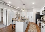 Thumbnail 7 of 26 - A kitchen with white cabinets and a black countertop.