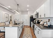 Thumbnail 3 of 26 - A modern kitchen with white cabinets and a black countertop.