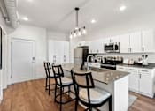 Thumbnail 2 of 26 - A kitchen with white cabinets and a wooden floor.