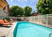 Thumbnail 30 of 41 - West Hills Apartments for Rent - Topanga Canyon - Exterior View of Gated Pool with Lounge Chairs and Dining Table