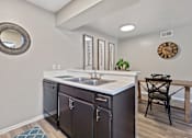 Thumbnail 10 of 27 - Kitchen sink with dark wood cabinets and dining area at The Colony Apartments, Universal City