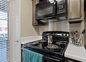 Thumbnail 11 of 27 - Electric stove with coil burners and overhead microwave at The Colony Apartments, Texas