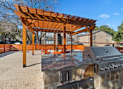 Thumbnail 7 of 27 - Outdoor grilling area with pergola and built in barbecue at The Colony Apartments, Universal City, TX