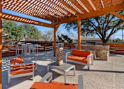 Thumbnail 8 of 27 - Outdoor lounge with pergola and stone fireplace at The Colony Apartments, Universal City, 78148