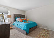 Thumbnail 15 of 27 - Bedroom with tufted headboard and colorful accent rug at The Colony Apartments, Universal City