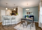 Thumbnail 10 of 21 - Kitchen with small dining room space. Breakfast bar with stools. Dining area with a table couch and two chairs at at Ascent at Mallard Creek Charlotte, NC