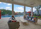 Thumbnail 16 of 21 - Pool view at Ascent at Mallard Creek Apartment Homes. Couches, table, cabanas, big pool, outside fans, and tile concrete flooring. At Ascent at Mallard CreekCharlotte, 28262