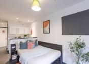 Thumbnail 5 of 8 - a bedroom with a bed and a kitchen in the background