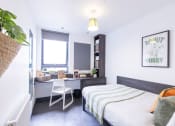 Thumbnail 2 of 8 - a bedroom with a bed and a desk and a window