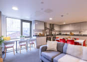 Thumbnail 2 of 8 - a living room with a kitchen and a couch